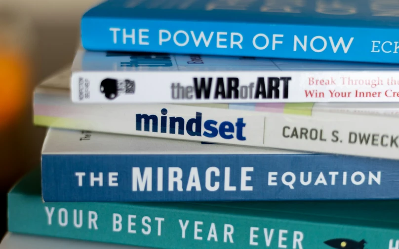 some books and one orange cup are stacked on each other