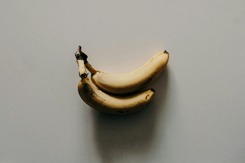 two bananas sitting together on top of a table