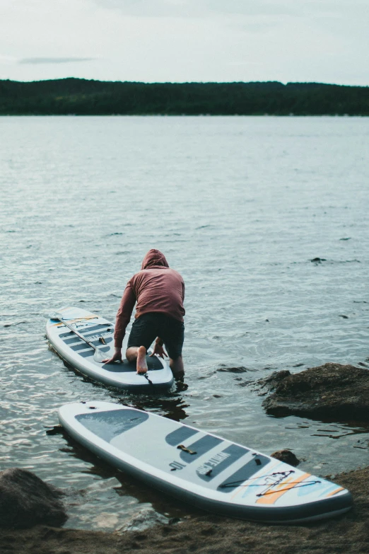 two men prepare their surfboards for going on a lake