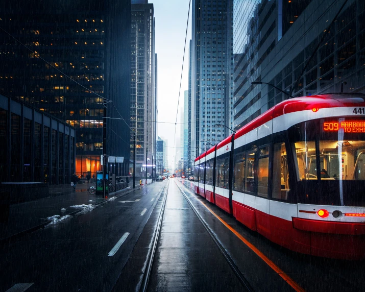 a long red and white trolley on street next to tall buildings