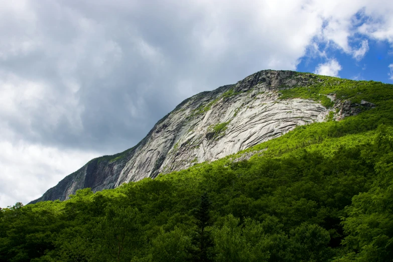 mountain with green trees and grey clouds on a partly cloudy day