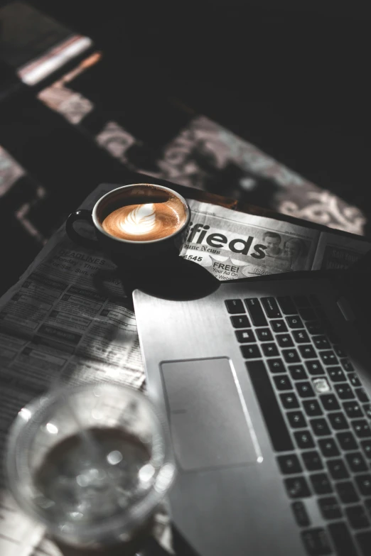 a close up view of the laptop with a cup of coffee and a glass on it