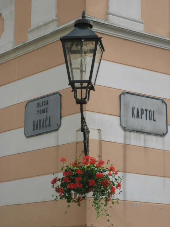 a lamp post holding flowers and a flower pot hanging on a wall