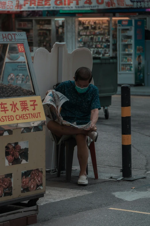 a man sitting down and reading a newspaper