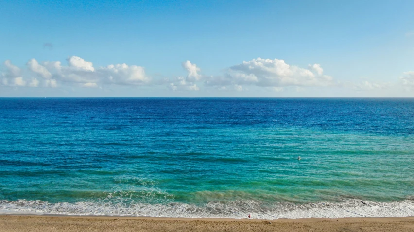 an ocean with waves breaking on it and sky in the background