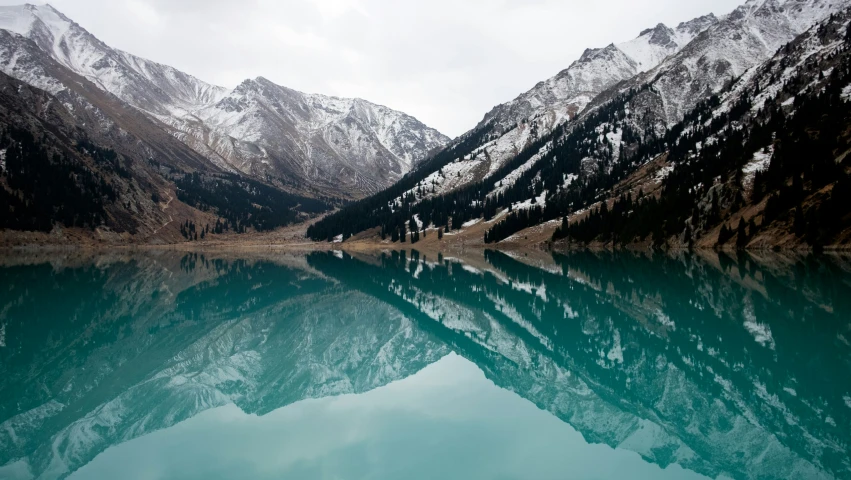 a mountain range with some clouds and water in front