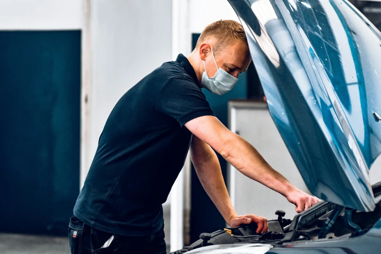 a man in black shirt working on the hood of his car