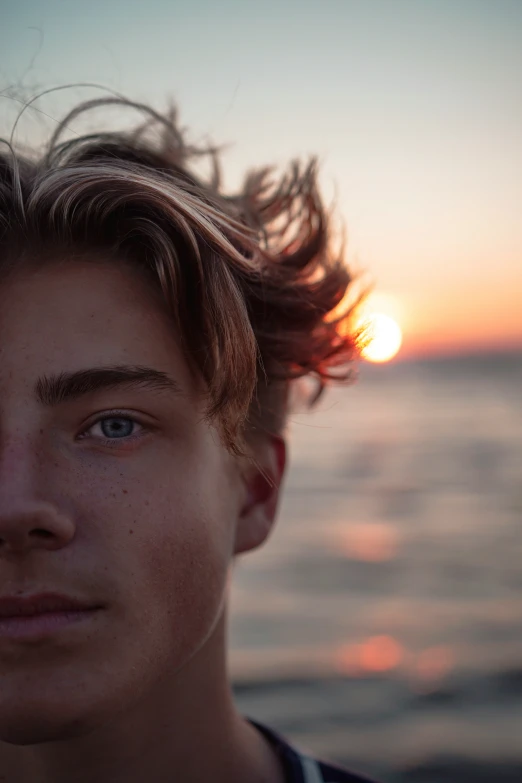 a close up of the face and chest of a man in front of a sunset