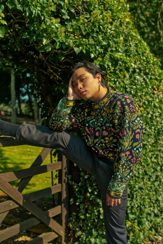 a man sitting on the edge of a fence leaning against the wooden rail