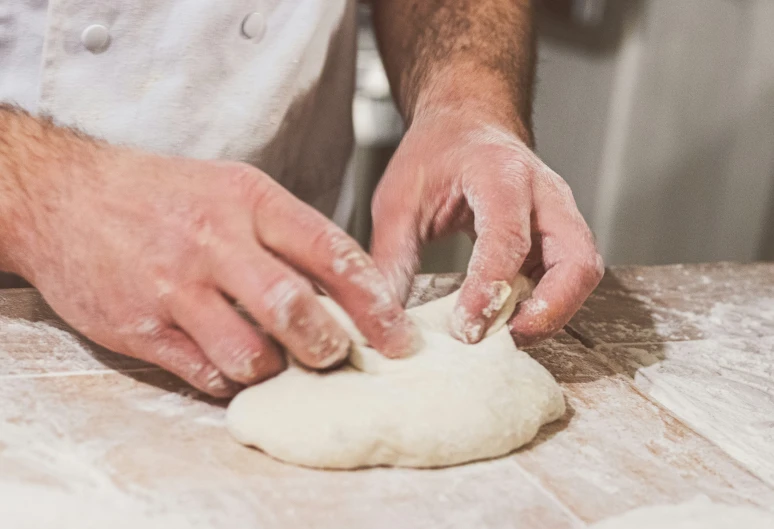 a person standing over a knead making bread