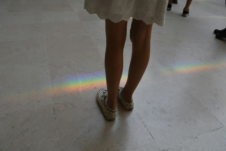 people walking by a rainbow of light on the floor