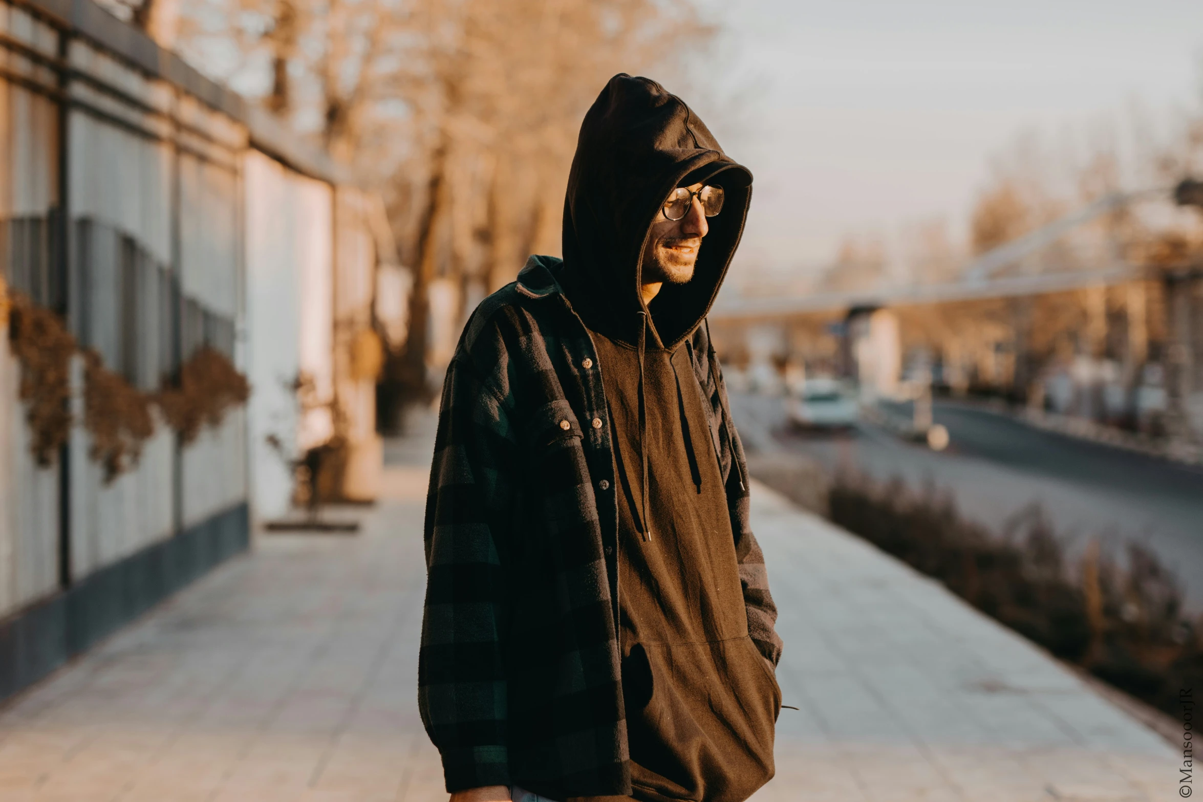 a man in hooded jacket and sunglasses on the side walk