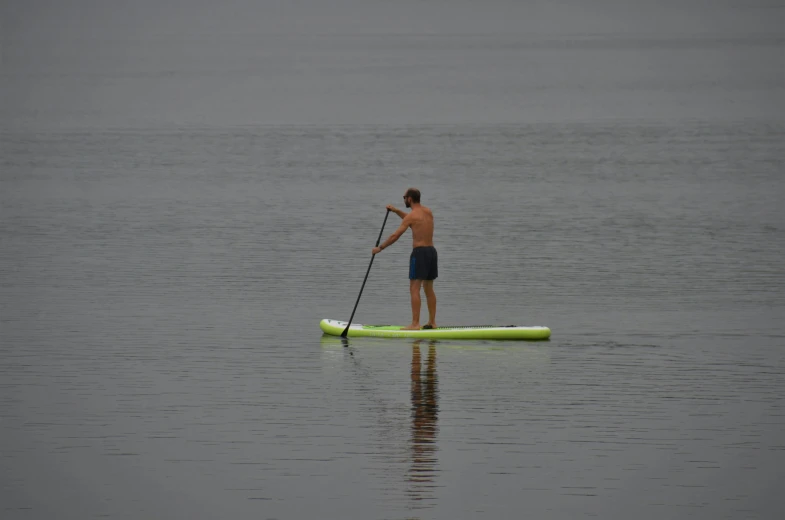 a man standing on the edge of a surfboard holding onto an oar