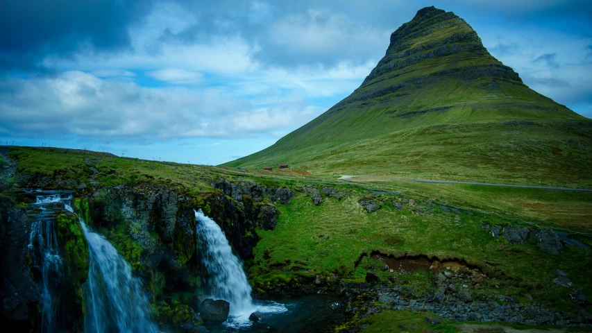 a very tall grass hill with some waterfalls