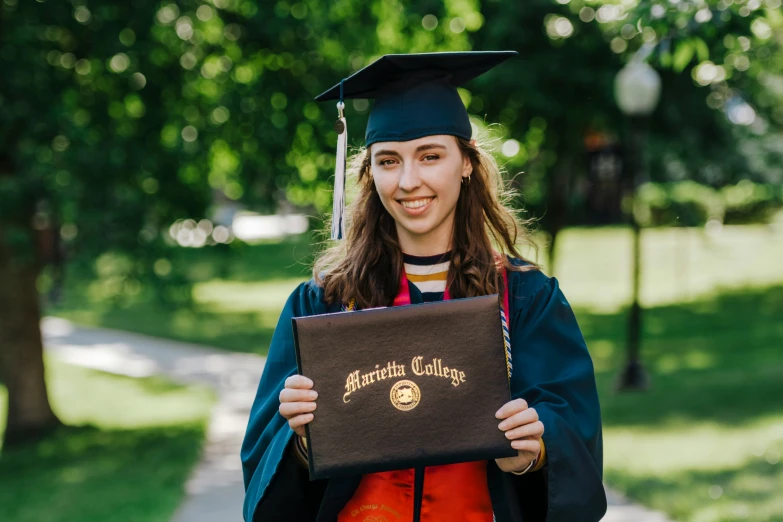 a girl in a cap and gown is holding her diploma