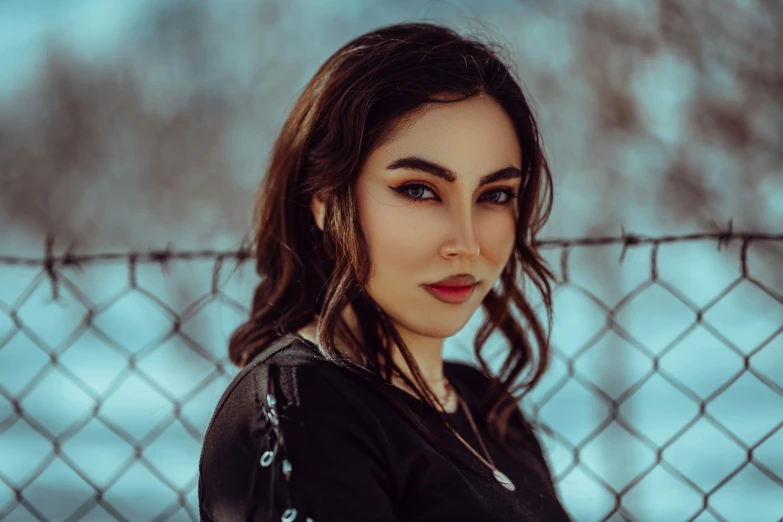 a woman standing behind a fence wearing a black shirt