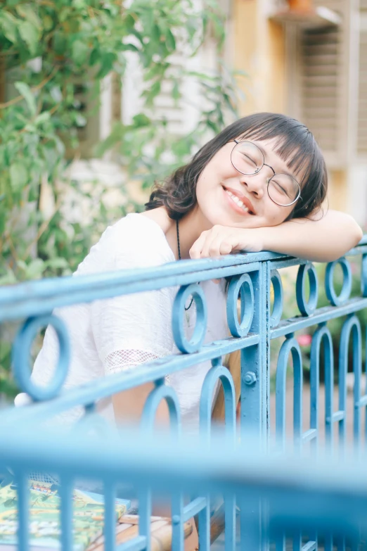 a girl in glasses is sitting on a bench outside