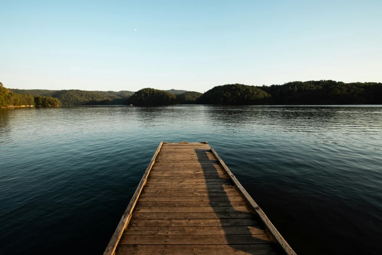 a pier leading out to a lake with a mountain in the background