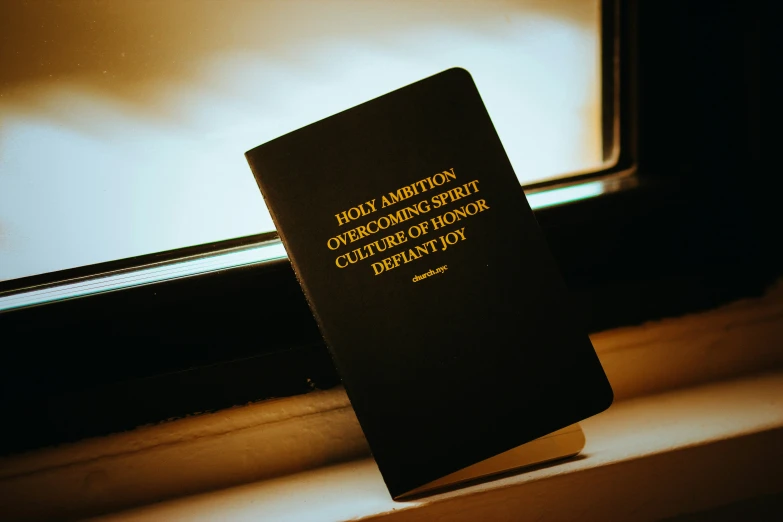 a black book with the cover sitting next to a window