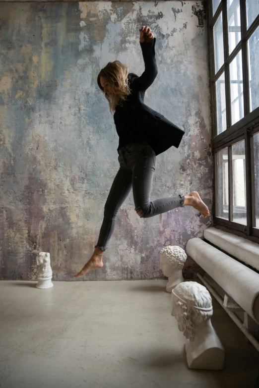a woman jumping up and down while holding onto a window