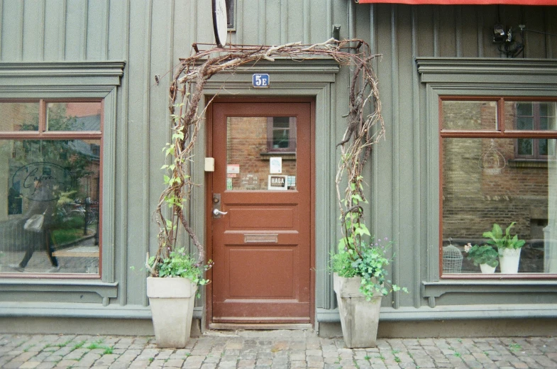 there is a red door with plants outside of the building