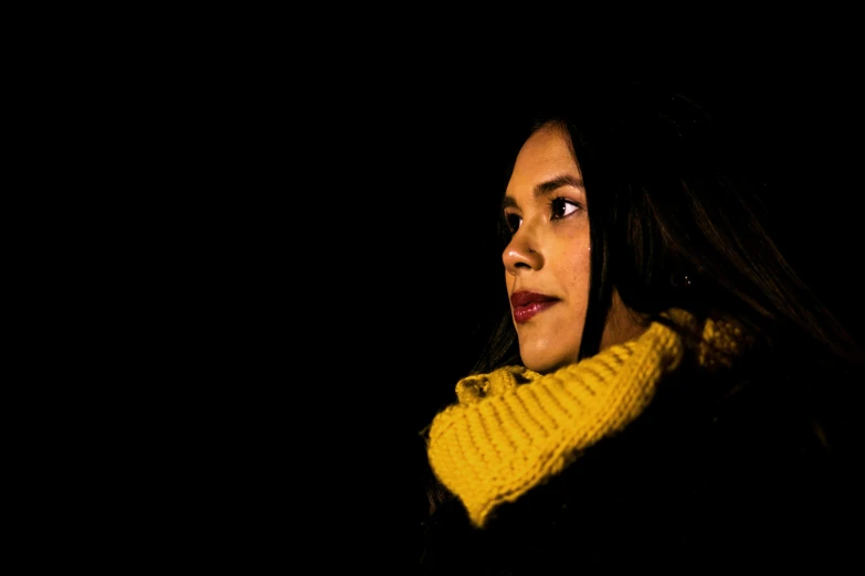 woman in yellow and black looking away at night