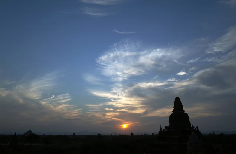 the sun is rising behind a dark, cloudy sky