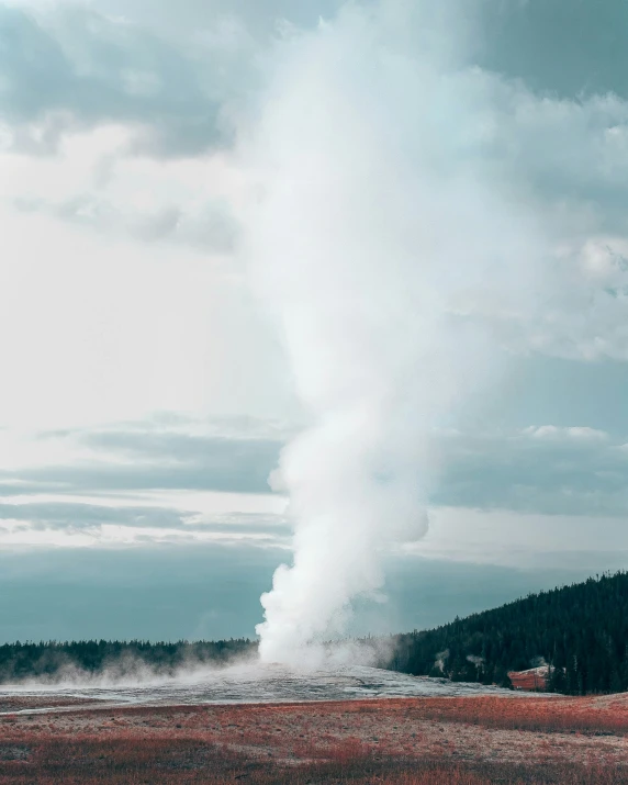 a geyser in the distance of a red field