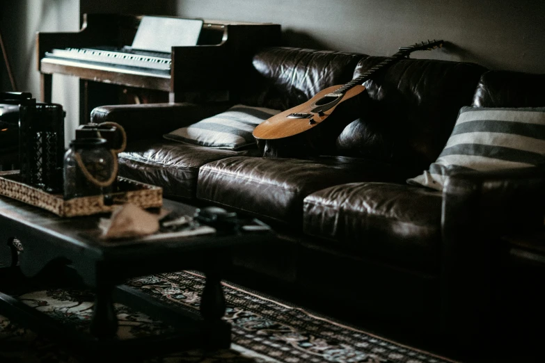 a living room with a black leather sofa and table and music equipment