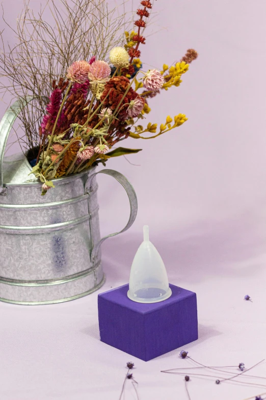 a small glass vase with dried plants and a purple vase