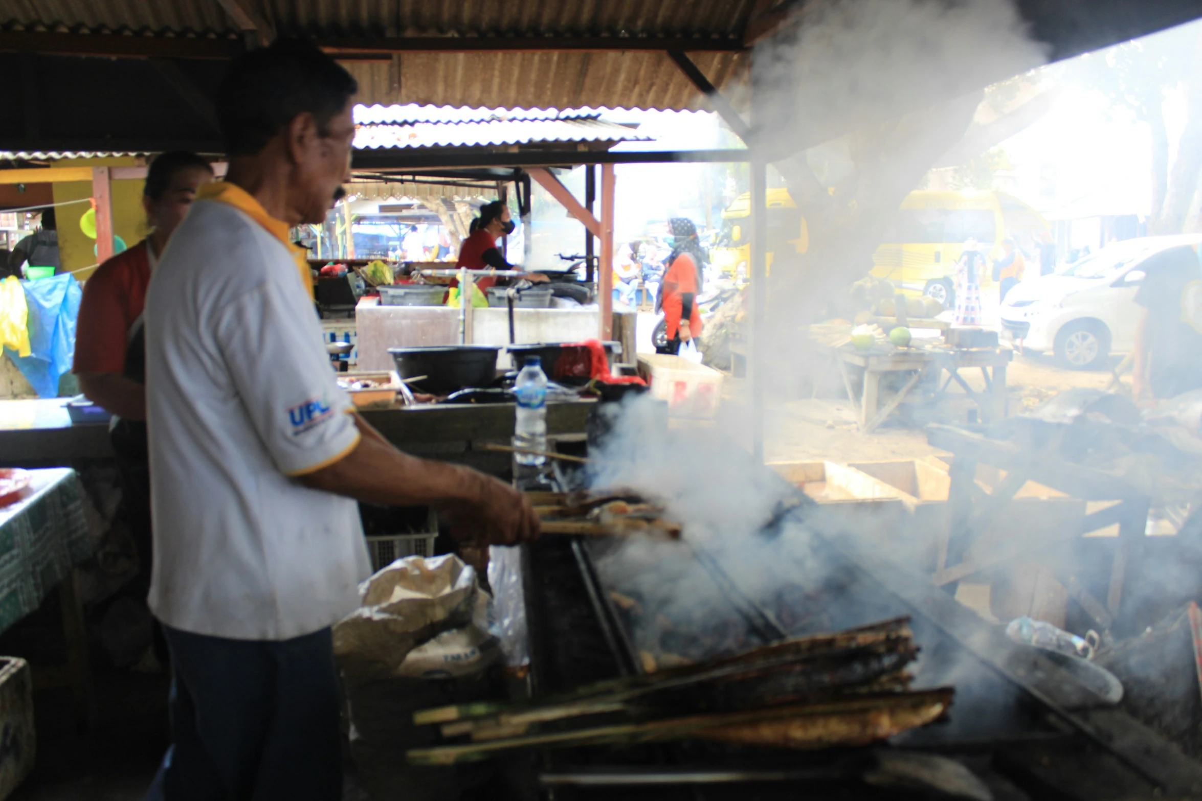 a man cooking on a large grill with  rods