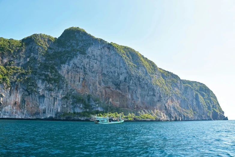 an island with a group of boats in the water next to a cliff