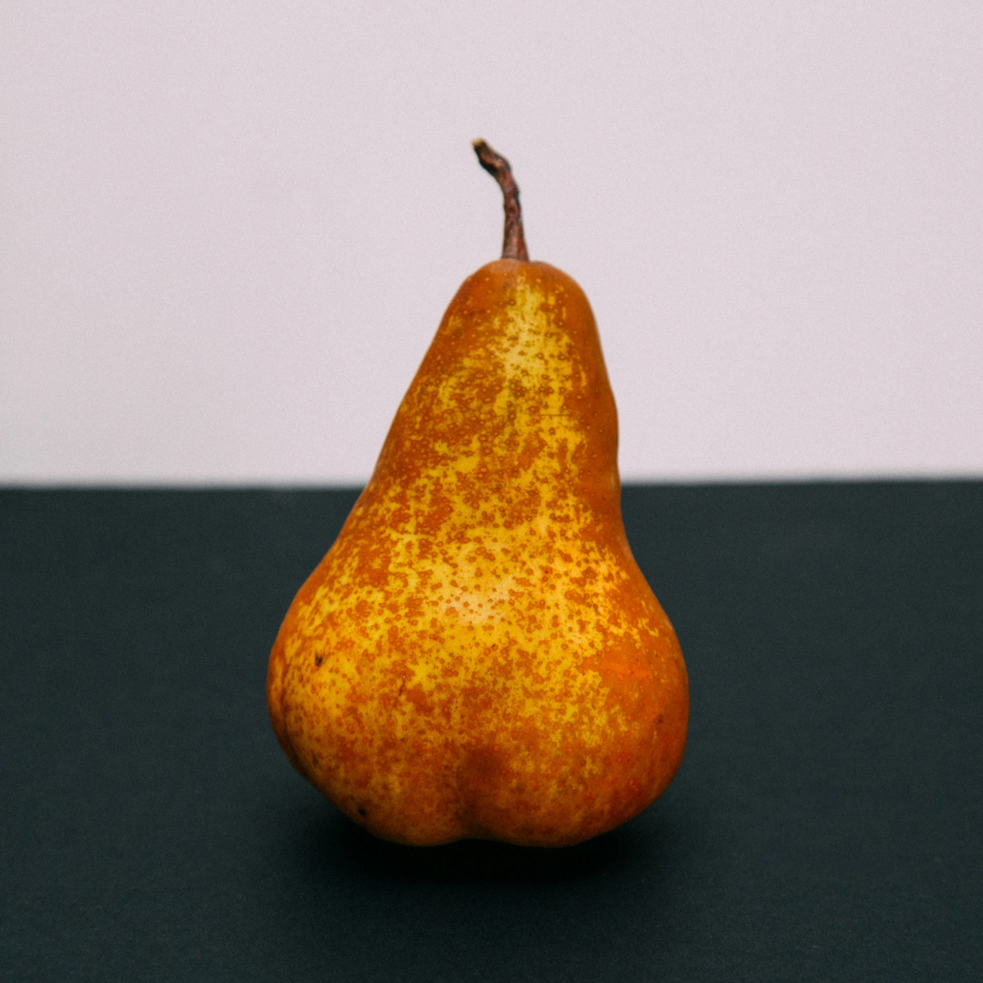an orange on a dark table with a white wall