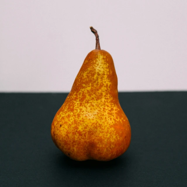 an orange on a dark table with a white wall