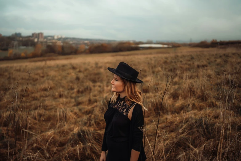 a woman wearing a hat standing in a large field