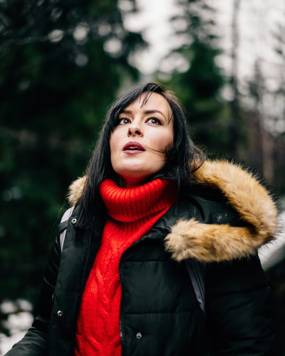 a woman standing on a path wearing a parka and matching a red scarf