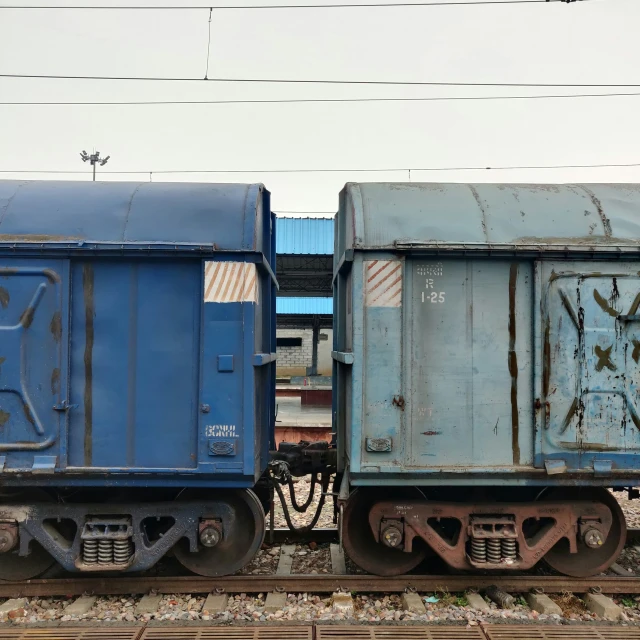 two old train cars sit on tracks in front of buildings