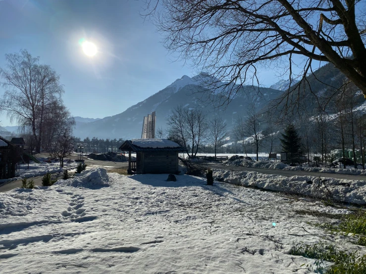 a small church in the snow with the sun behind it