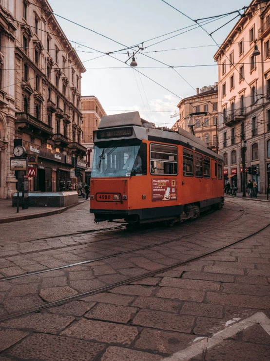 an orange trolley traveling down a street next to buildings