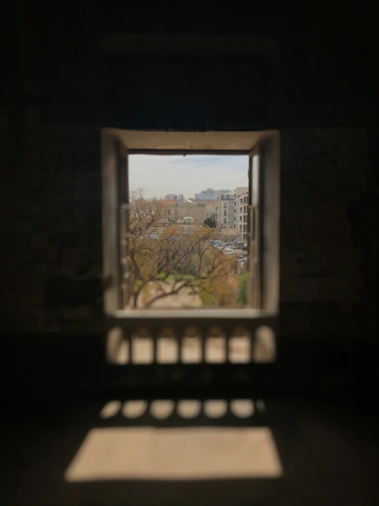 looking out a window in a stone walled structure towards a cityscape