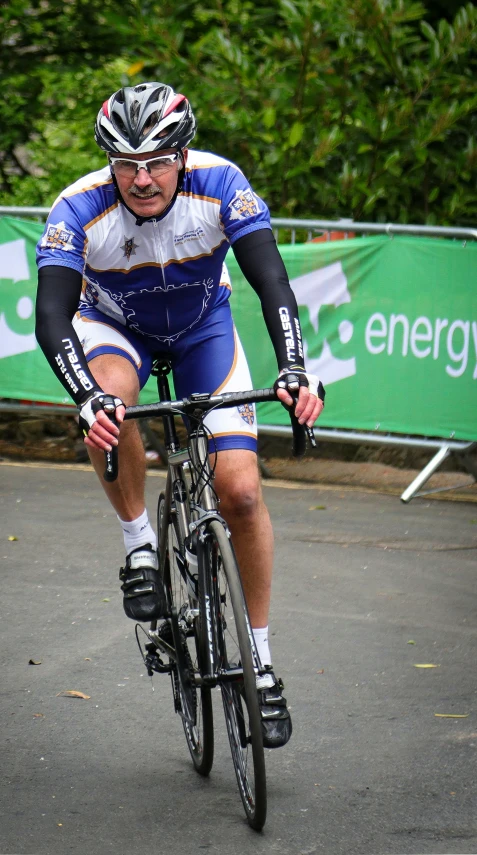 the cyclist is wearing blue jersey, while riding his bicycle