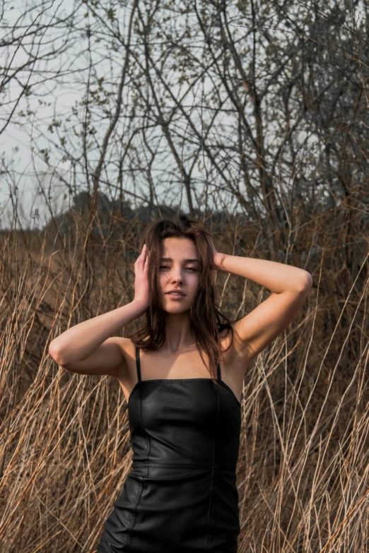 a woman with her hand on her head in front of tall grass