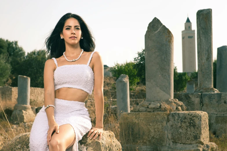 a woman sitting on a stone wall in front of many graves