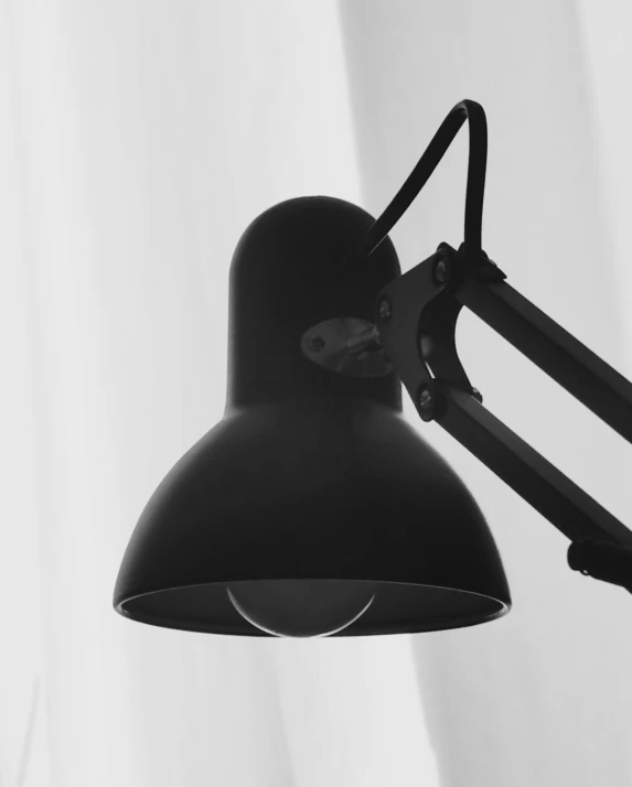 a black lamp with the light on and the wall behind it