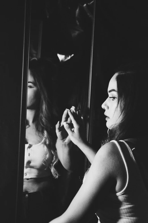 a black and white po of a woman looking into the mirror