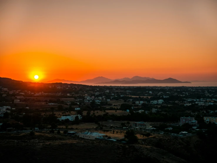 the sun is setting over a mountain town