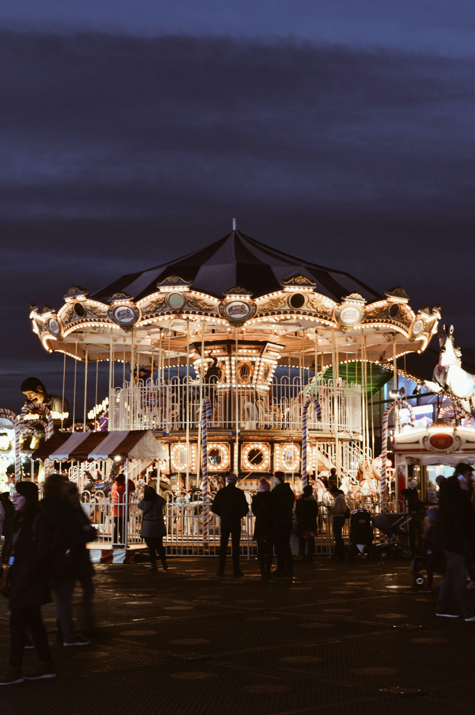 a carousel at night during the evening in front of a crowd of people