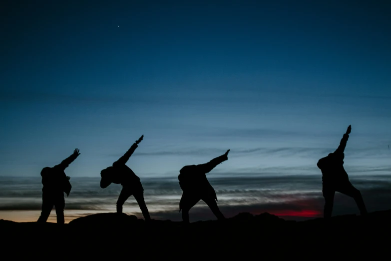 silhouetted women stretching with arms raised to the sky