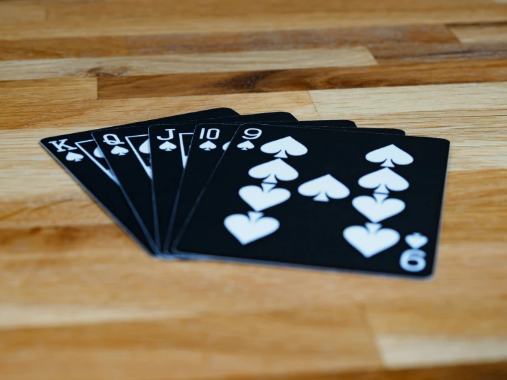 five playing cards are lying on a wooden surface