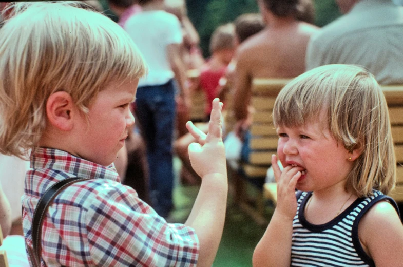 two young children sit outside and talk